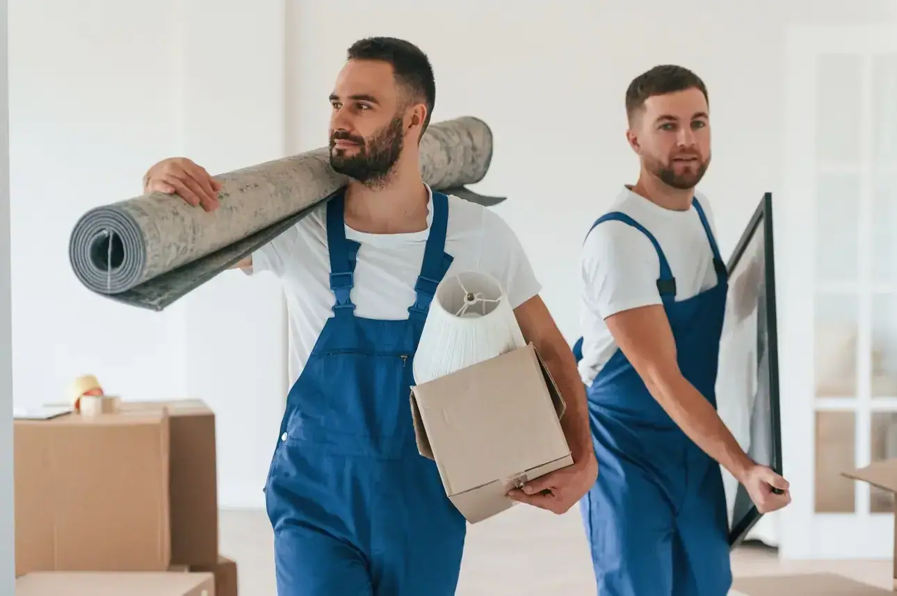 Möbelpacker tragen einen Teppich und ein Bild aus der Wohnung