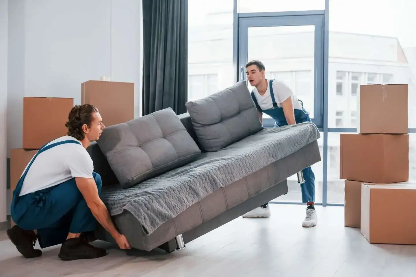 Zwei Möbelpacker tragen ein Sofa durch eine Wohnung in Wien